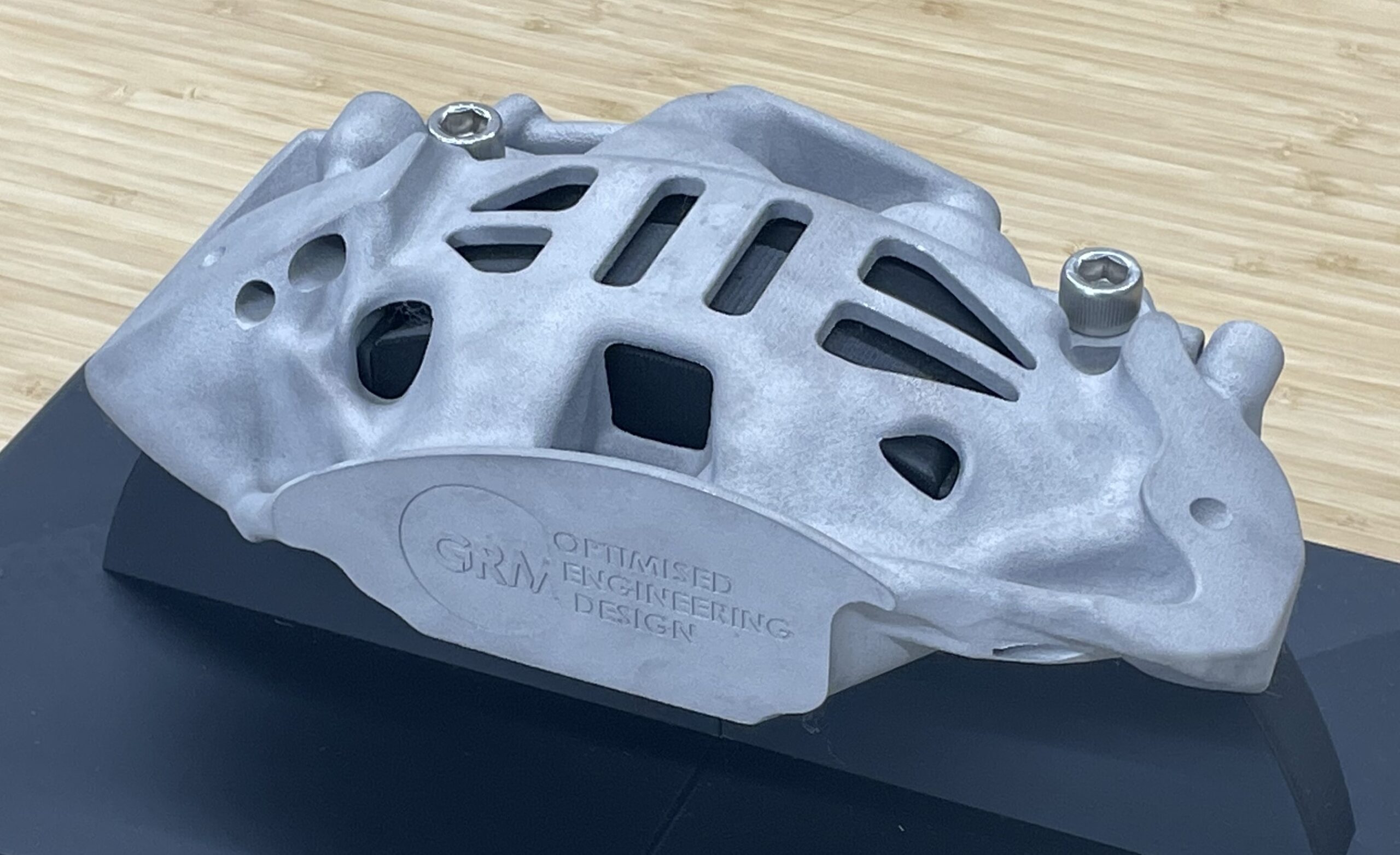 トポロジー最適化設計したブレーキキャリパーを3Dプリンターで出力したもの。材質はアルミ。