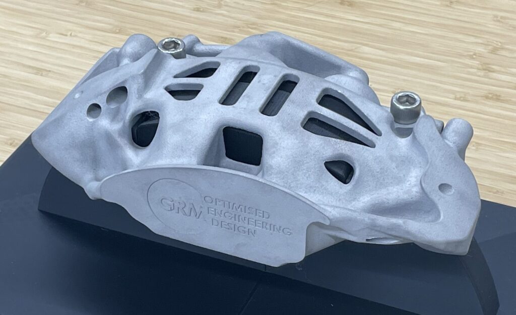 トポロジー最適化したブレーキキャリパーを３Dプリンターで出力したもの。材質はアルミ。